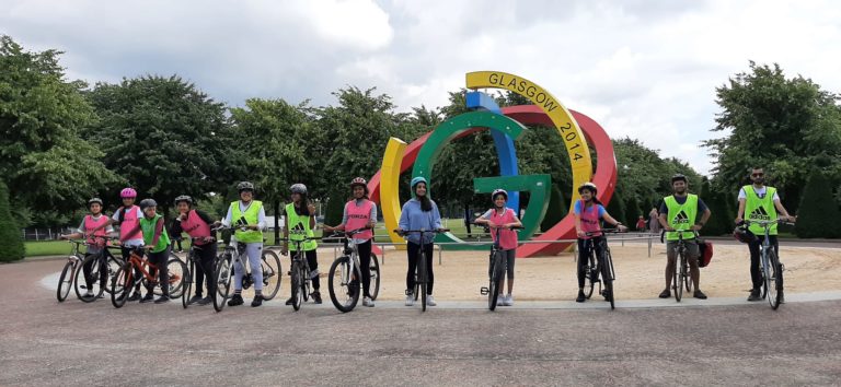 Group of young people standing outside in front of a coloured sculpture on bikes