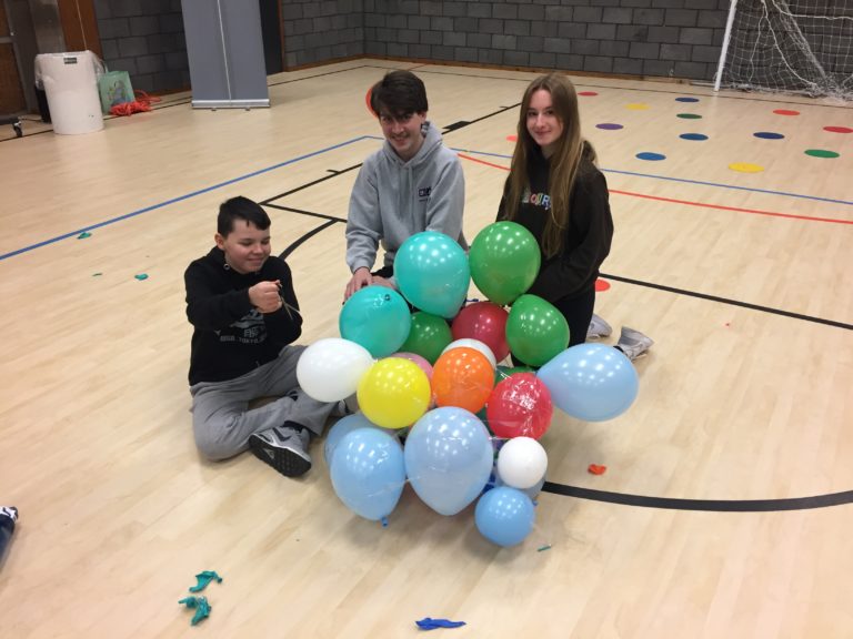 Young people in a sports hall with a bunch of balloons