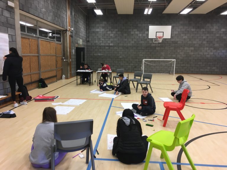 Young people sat in a sports hall with coloured chairs