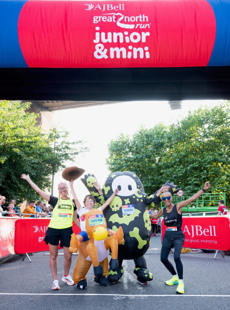 Adele Roberts and 2 kids from Kayaks posing under Great North Run finish line