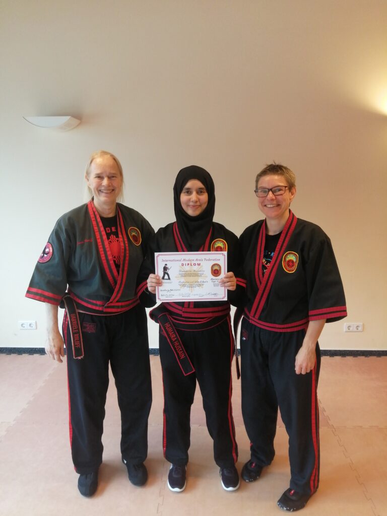 three people from a martial arts group posing with a certificate