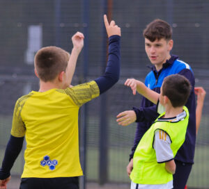 Image of two young football players and a football coach