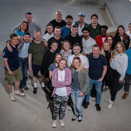 Large group of adults dresses casually all looking upwards to the camera and smiling.