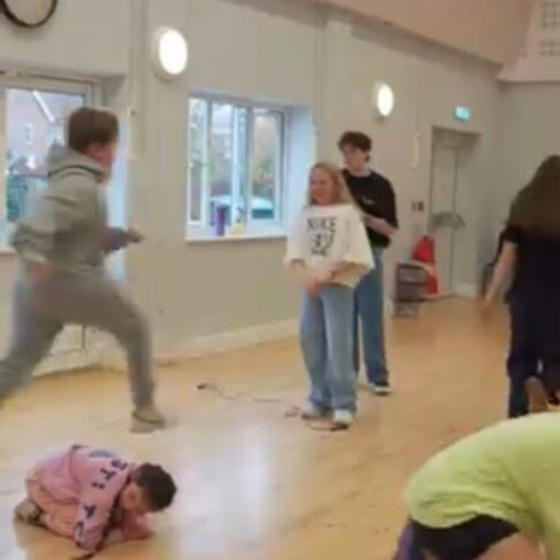 Young people in hall playing jumping and running games
