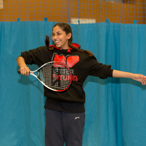 Girl smiling while holding a tennis racquet