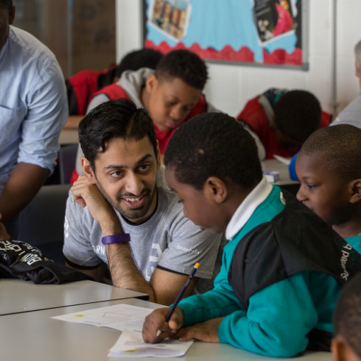 Man helping a young boy in a classroom