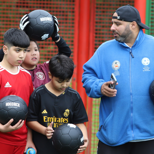 Male coach with three young male footballers