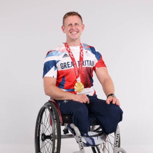 Aaron Phipps sat in his wheelchair with a Great Britain paralympic t-shirt on and his gold medal round his neck