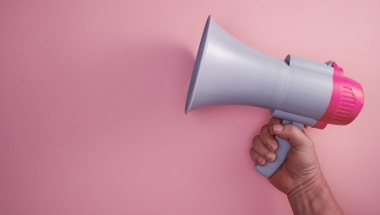 pink background, hand holding a megaphone