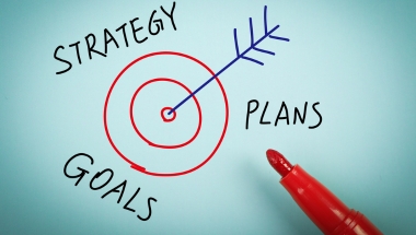 picture of a target, with strategy plans and goals written on the outside, with an arrow in the middle.