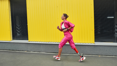 amputee woman in a pink track suit running in an urban environment